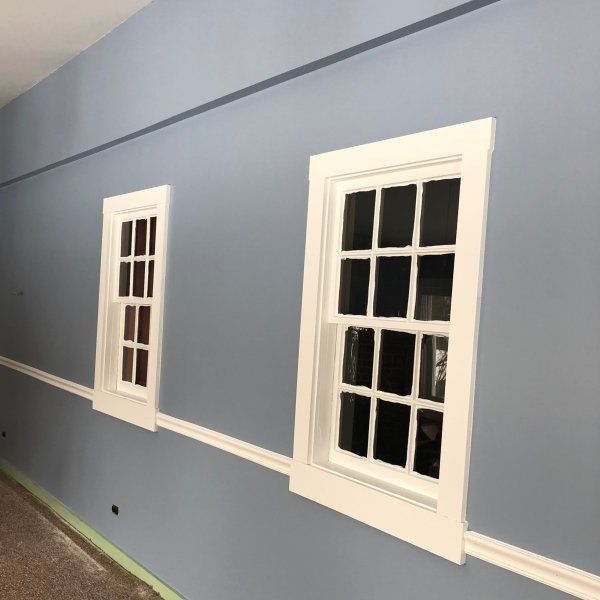 three windows on the side of a wall in a room that is painted blue and white