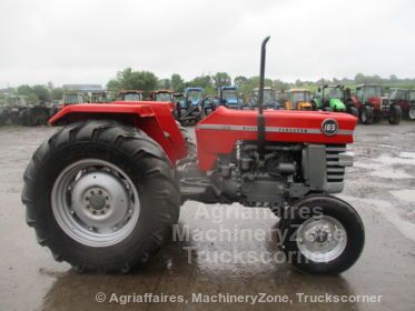 a red tractor parked in a parking lot with other tractors behind it on a rainy day