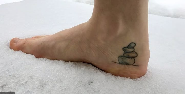 a person standing on top of snow covered ground with rocks in the middle of their foot