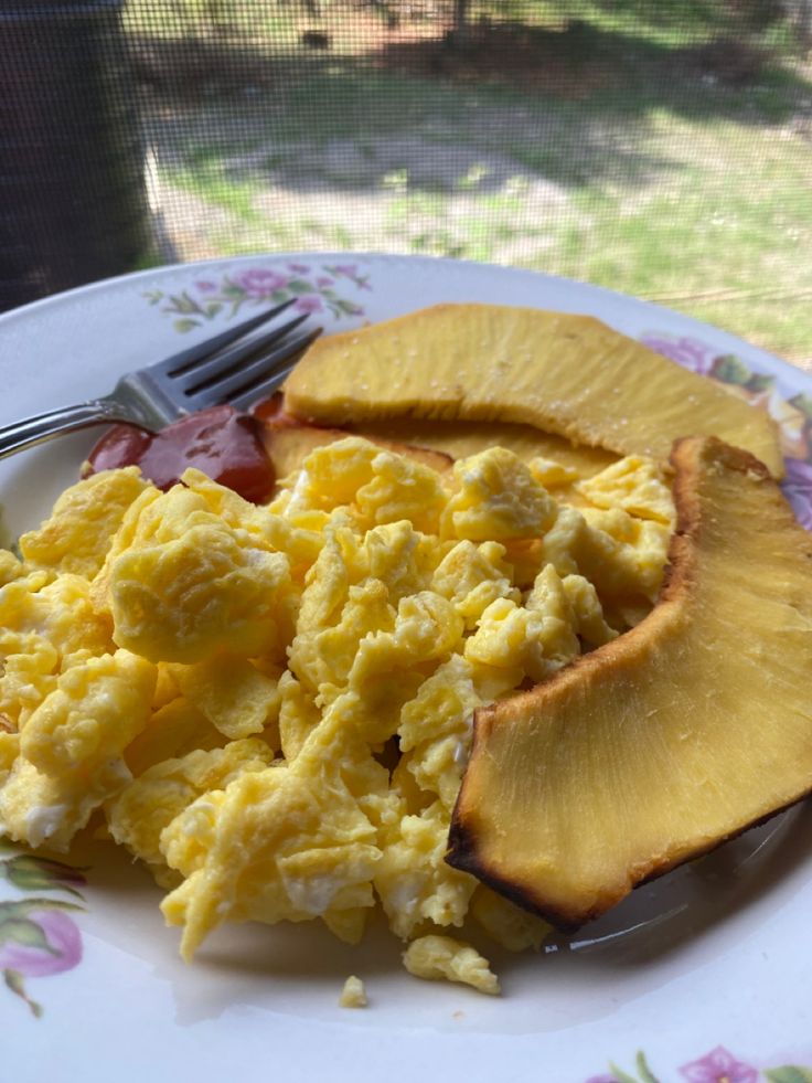 a plate with eggs, potatoes and tomatoes on it next to a glass door outside