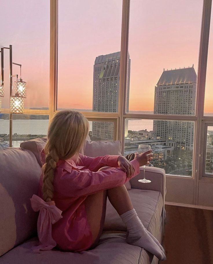 a woman sitting on top of a couch next to a window