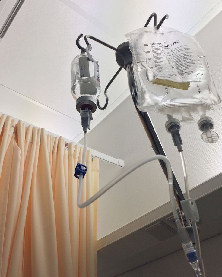 a hospital room with medical equipment hanging from the ceiling and drapes on the walls