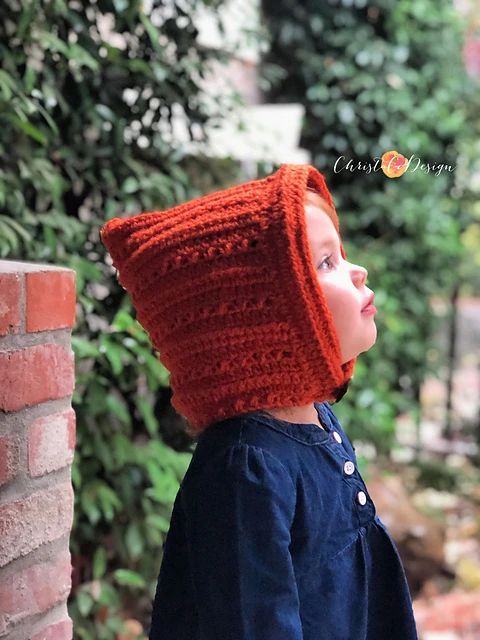 a young child wearing an orange crocheted hat