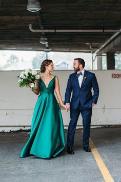 a bride and groom holding hands in an empty parking garage with white flowers on their bouquets