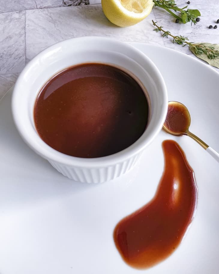 a white plate topped with a bowl of sauce and a lemon wedge next to it