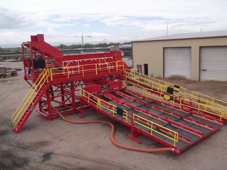 a large red machine sitting in the middle of a parking lot next to a building