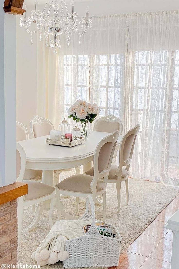 a white dining room table with chairs and a basket on the floor next to it