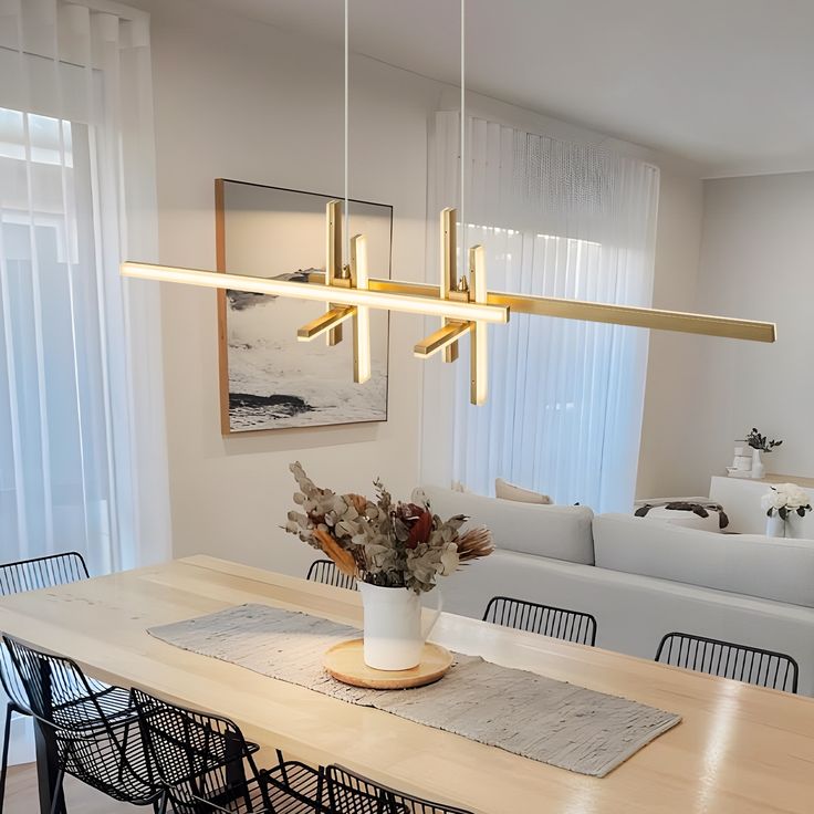 a dining room table with flowers in a vase on it and hanging from the ceiling