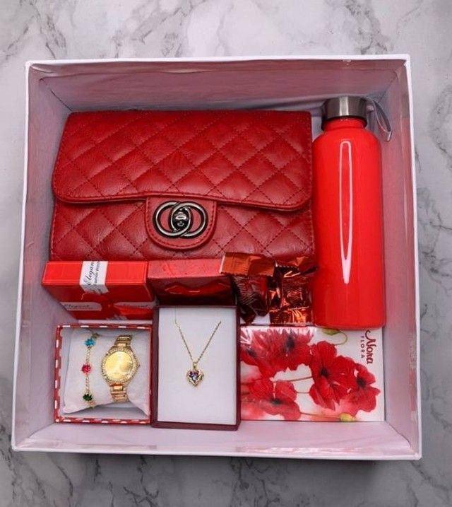 the contents of a women's red purse are neatly packed in a gift box