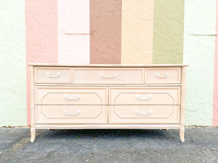 an old dresser in front of a multicolored wall