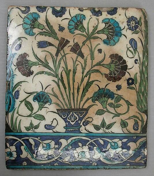 an ornately decorated tile with blue flowers and green leaves on the bottom, is shown