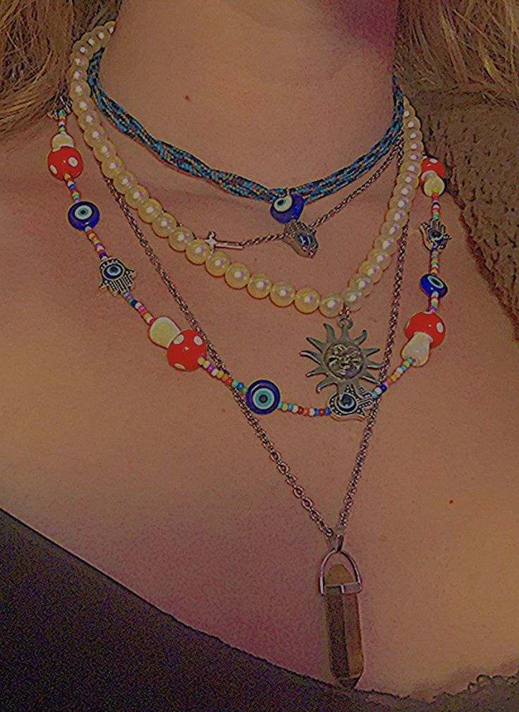 a close up of a woman wearing a necklace with beads and charms on it's neck