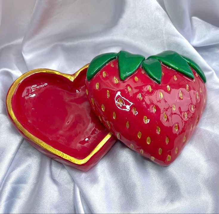 two strawberry shaped dishes sitting on top of a white cloth