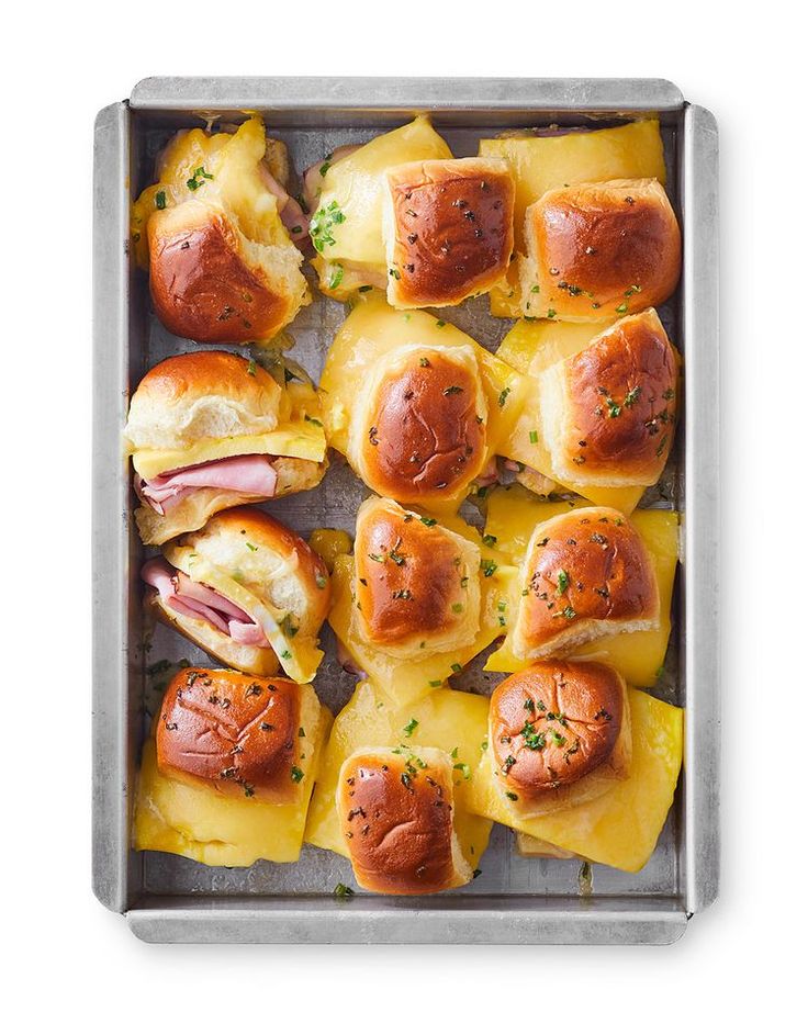 ham and pineapple sliders in a baking pan with cheese on the side, ready to be eaten