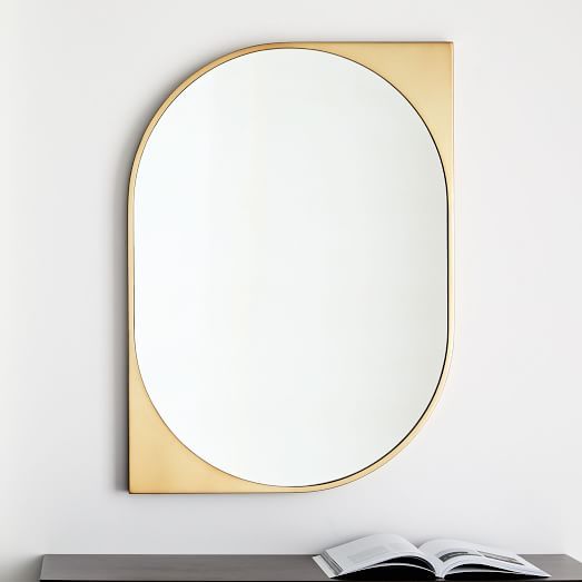 an open book sitting on top of a wooden table next to a round shaped mirror