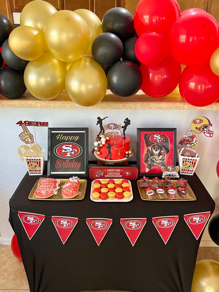 a table topped with lots of red and gold balloons next to a black table cloth