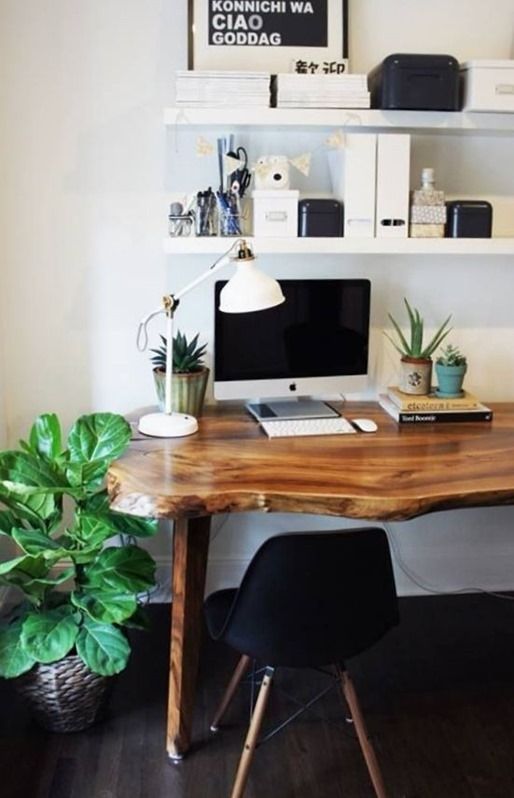 a wooden desk with a computer on it and some plants in front of the monitor