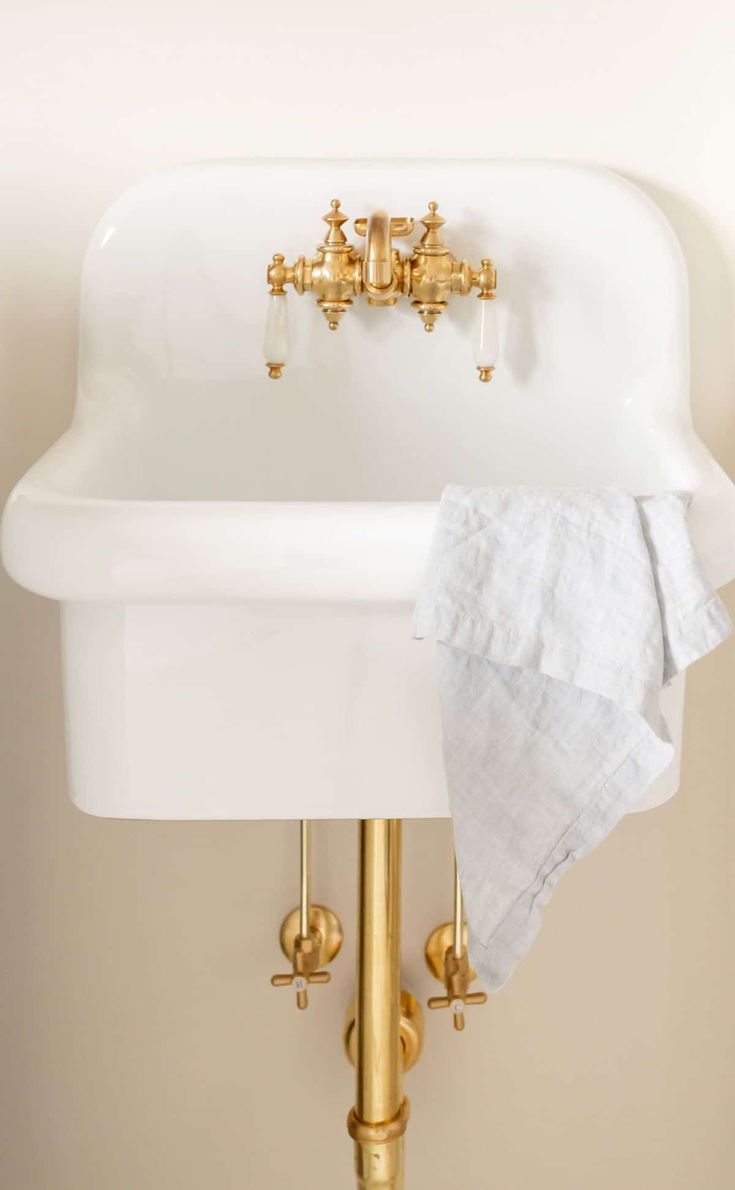 a white sink sitting under a golden faucet