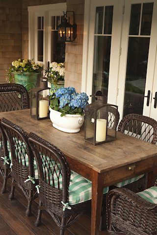 a wooden table sitting on top of a wooden floor next to a white vase filled with flowers