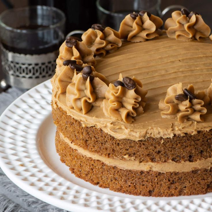 a frosted cake on a white plate sitting on a table