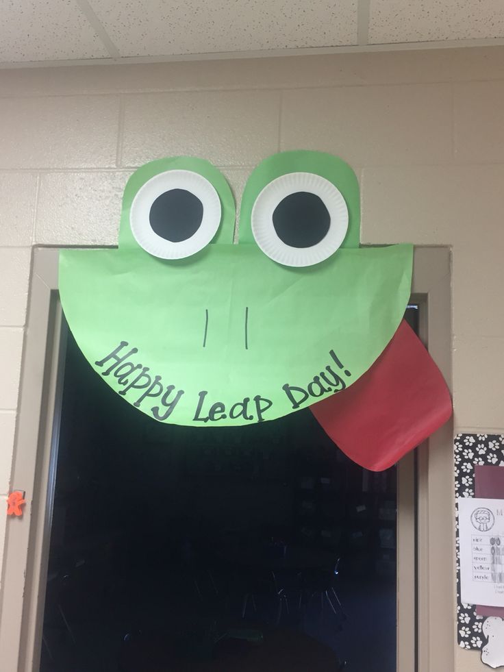 a green frog head hanging from the side of a door with happy leap day written on it