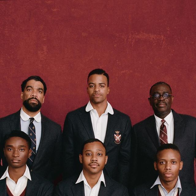 a group of men standing next to each other wearing suits and ties with one man in the middle