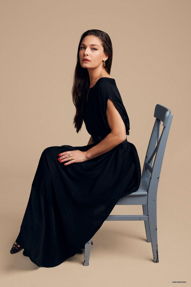 a woman sitting on top of a wooden chair