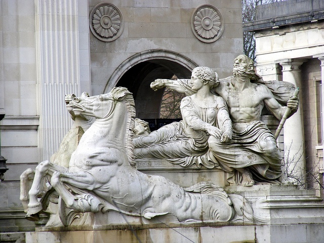 the statue is in front of an old building with statues on it's sides