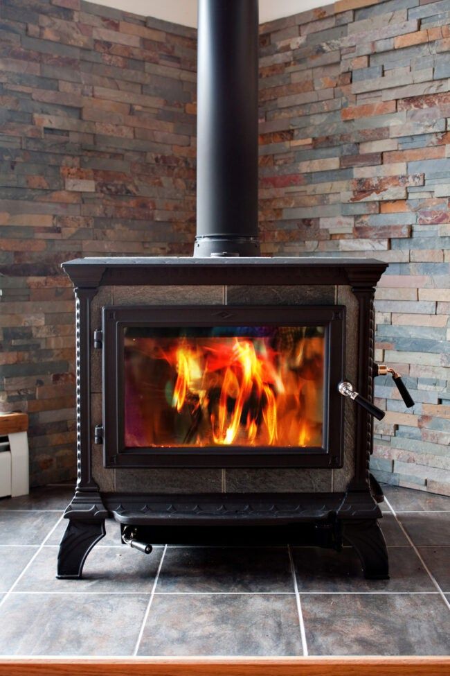 a wood burning stove sitting inside of a living room next to a brick wall and floor