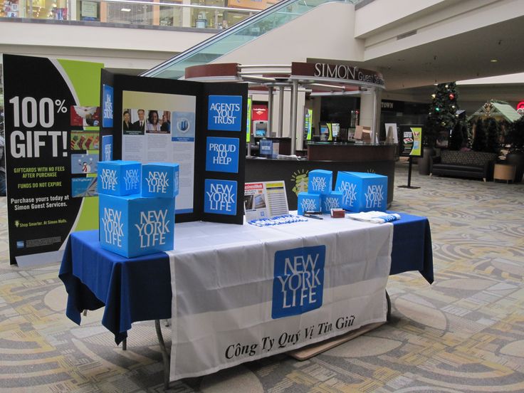 a table with new york life merchandise on it in a shopping mall, next to a sign that says $ 100 off