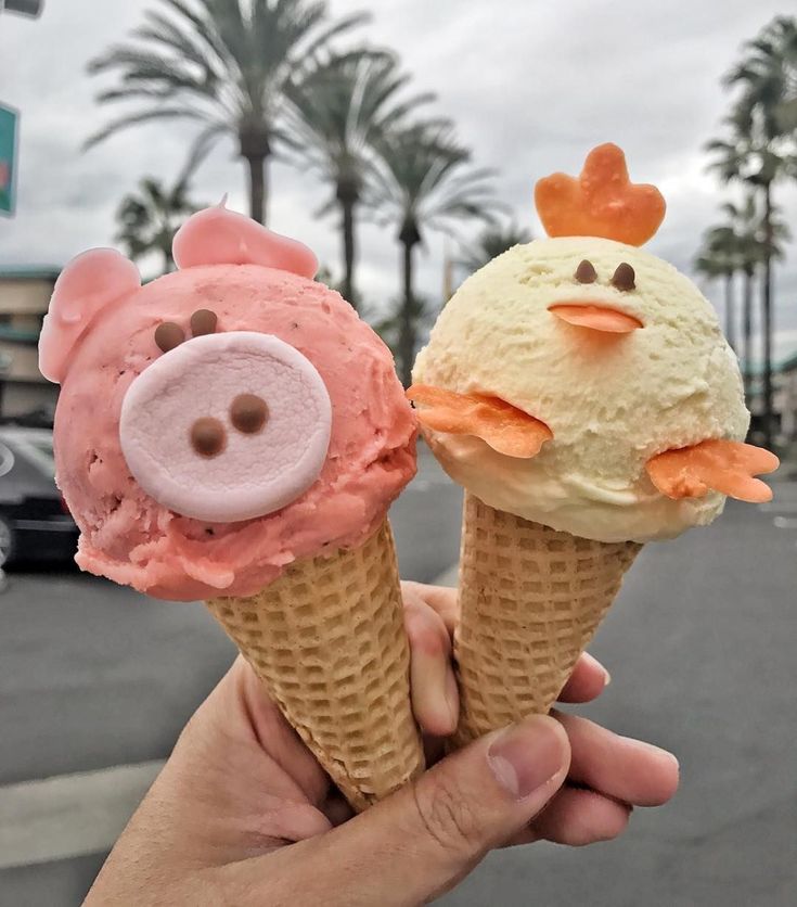 two ice cream cones with faces on them in front of a parking lot and palm trees