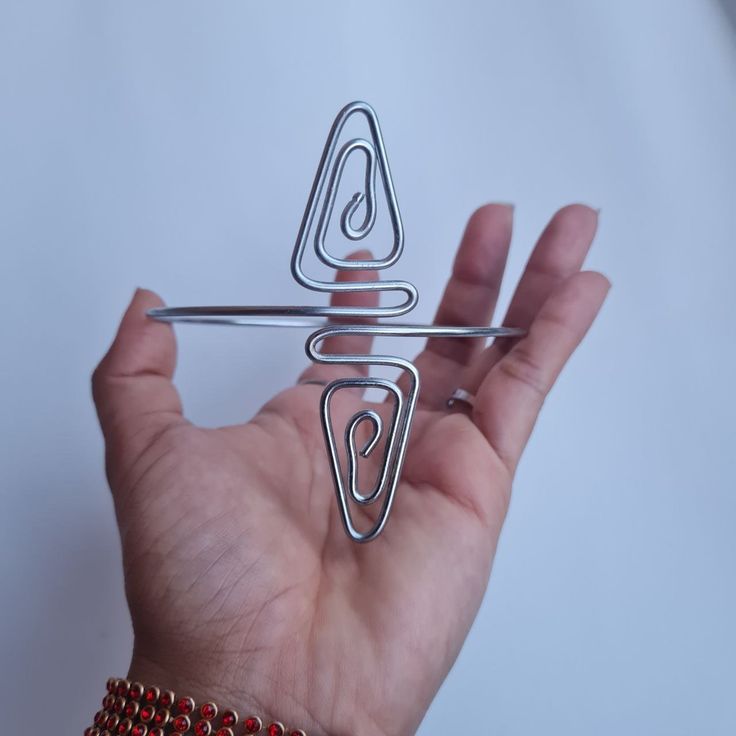 a hand holding a metal object in it's right hand and another wire on the left