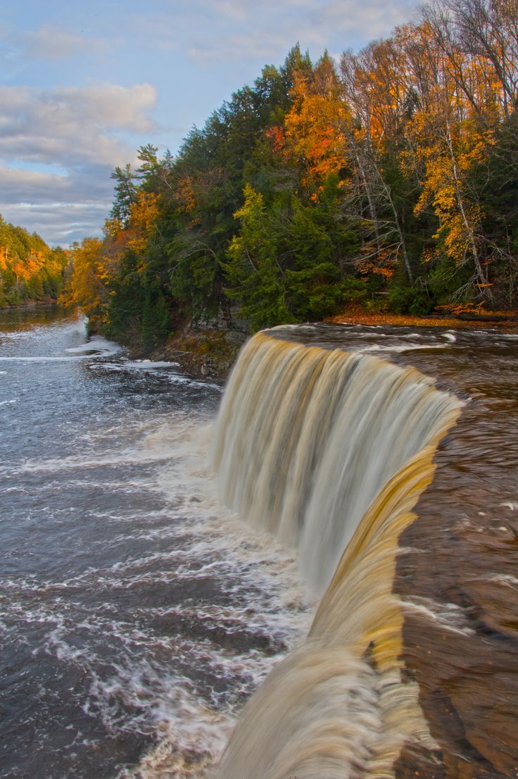 the water is flowing over the rocks and into the river to see what looks like fall foliage