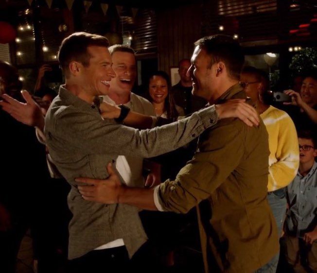 two men hugging each other in front of a group of people on the dance floor