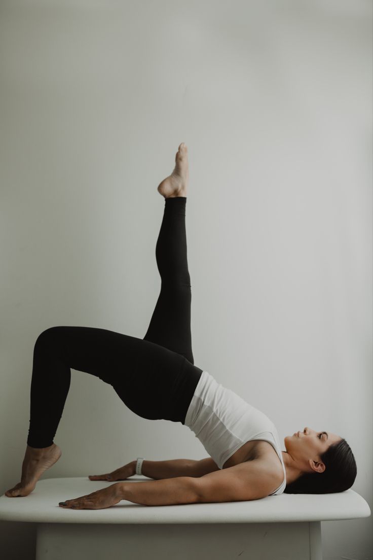 a woman in black and white doing a yoga pose on top of a countertop