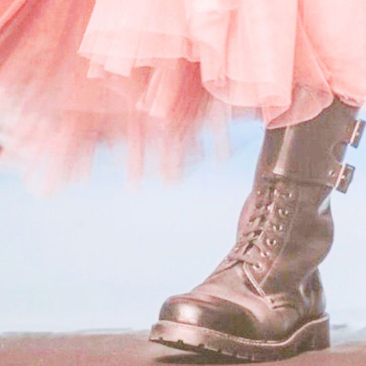 a woman's legs wearing black boots and a pink dress