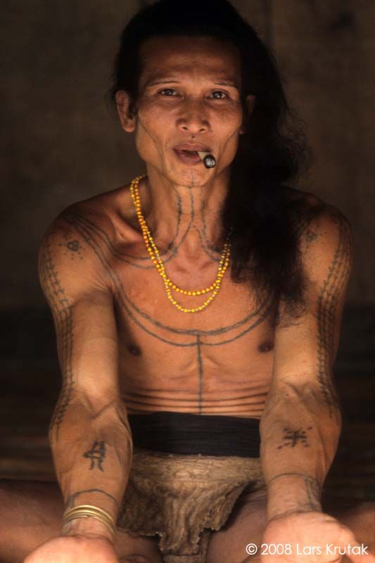 a man with tattoos sitting on the ground