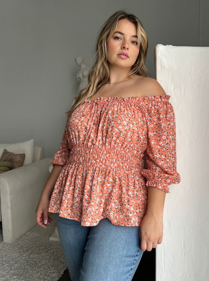 The fun and flattering Plus Size Elasticized Floral Blouse is a great addition to any warm-weather outfit collection. This plus size top is great worn with a cute pair of trending jeans for an effortless look or dress it up a bit with some statement pants. This blouse features an elasticized top hemline that can be worn on or off the shoulder, a decorative tie on the bust, and elastic around the waistline and at the ends of the 3/4 length sleeves. The material is a non-stretchy woven. This top i Peach Tops For Summer Brunch, Casual Peach Blouse For Brunch, Summer Peach Blouse For Brunch, Summer Peach Tops For Day Out, Peach Feminine Blouse For Day Out, Feminine Peach Blouse For Day Out, Peach Blouse For Spring Beach Occasions, Peach Blouse For Beach In Spring, Peach Blouse For Beach, Spring Season