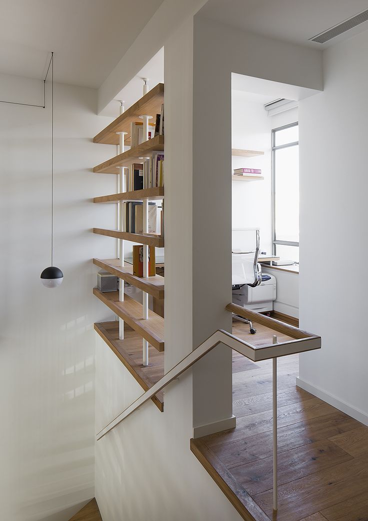 the stairs are made of wood and have bookshelves on each side, along with metal handrails