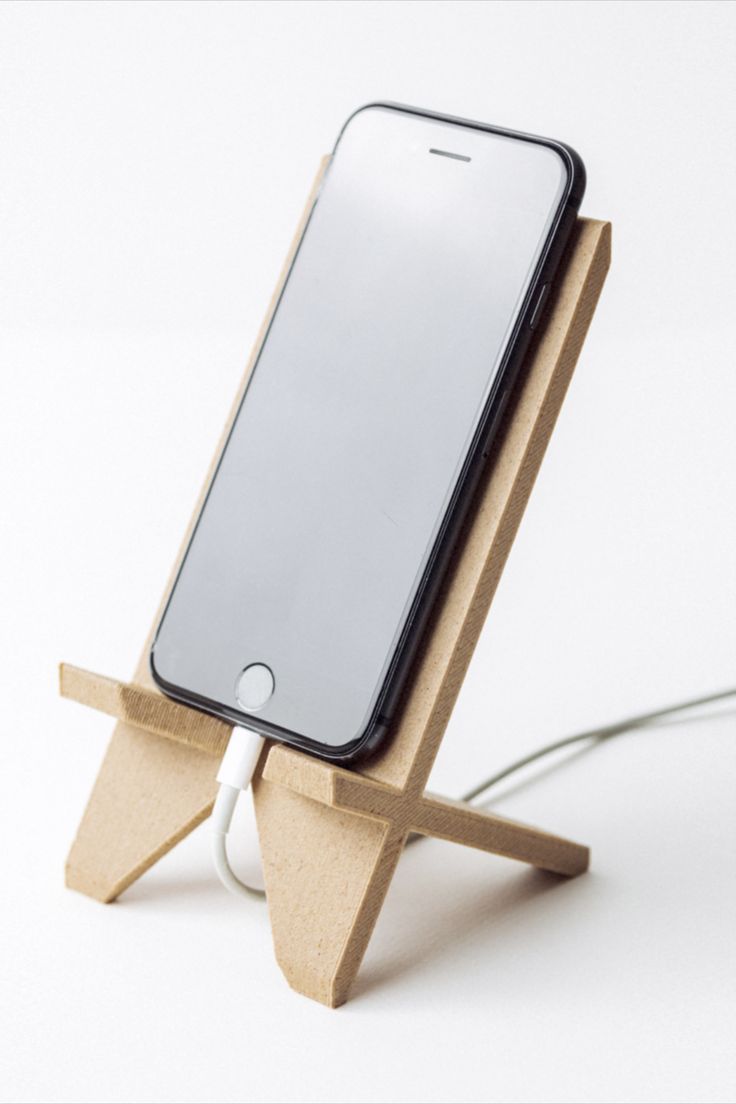 an iphone on a wooden stand with a charger plugged into the charging station