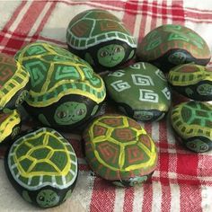 painted rocks with turtle designs on them sitting on a red and white checkered table cloth