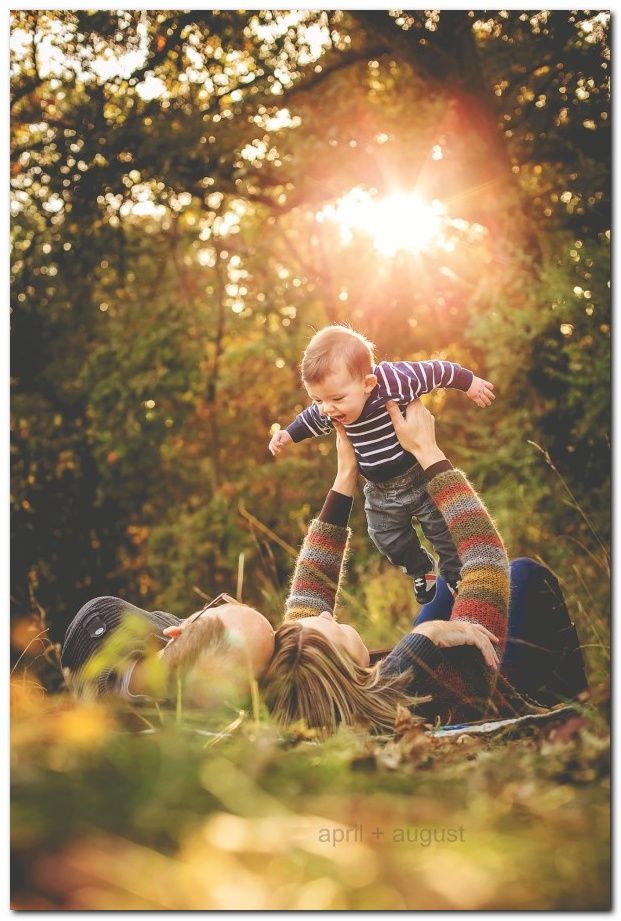 a woman holding a small child up in the air while laying on top of her