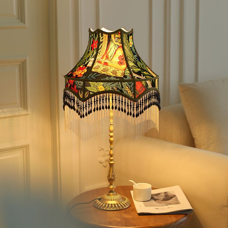 a table with a lamp on top of it next to a book and coffee cup