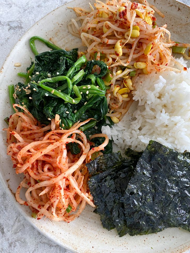 a white plate topped with rice and veggies on top of a marble table