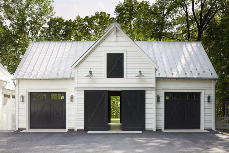 a white house with black garage doors and windows