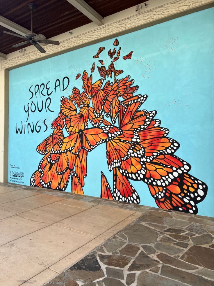 a mural on the side of a building with orange and black butterflies painted on it