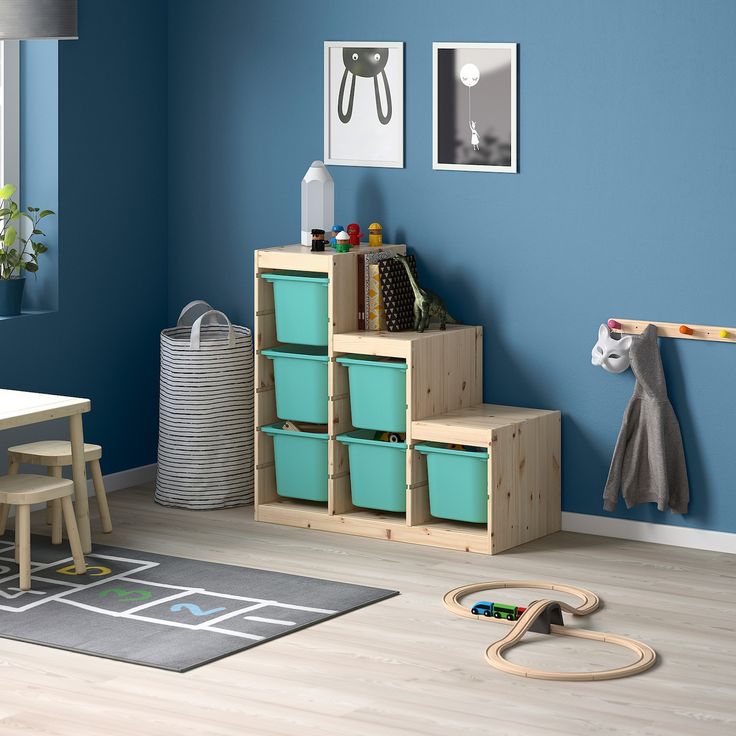 a child's playroom with blue walls and wooden toys on the floor in front of it