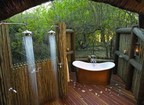 an outdoor bathroom with a tub and shower