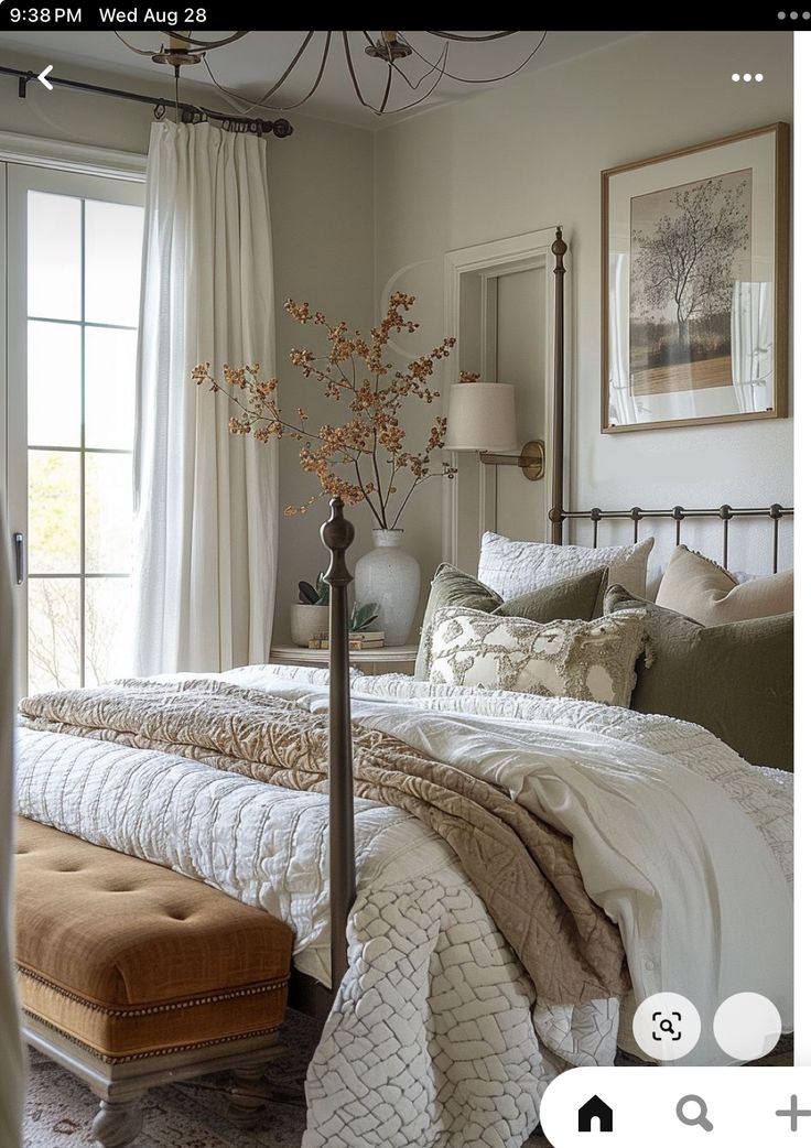 a large bed sitting next to a window in a room with white curtains and pillows