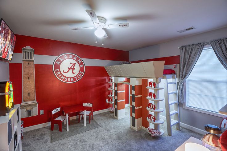 a bedroom with red and white walls, bunk beds and desks in the corner